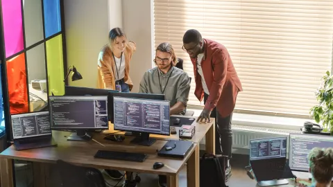 Office workers huddling around a computer screen.